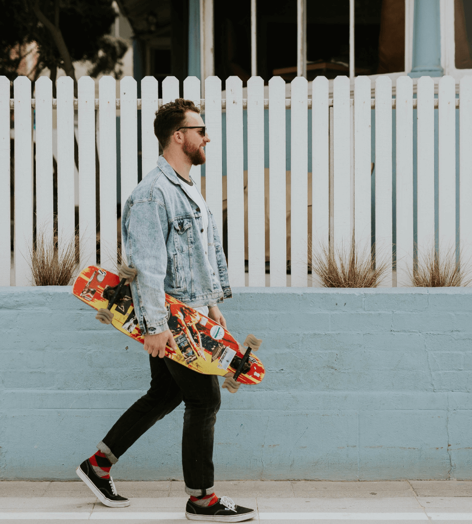 Man walking down the street with skateboard in hand